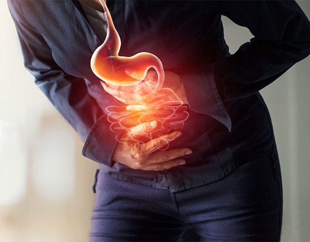 Person holding midsection with glowing digestive system graphic
