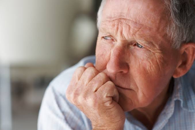 Older man looking thoughtful with hand on chin