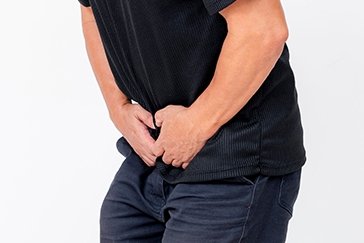 Man holding lower abdomen representing urinary symptoms