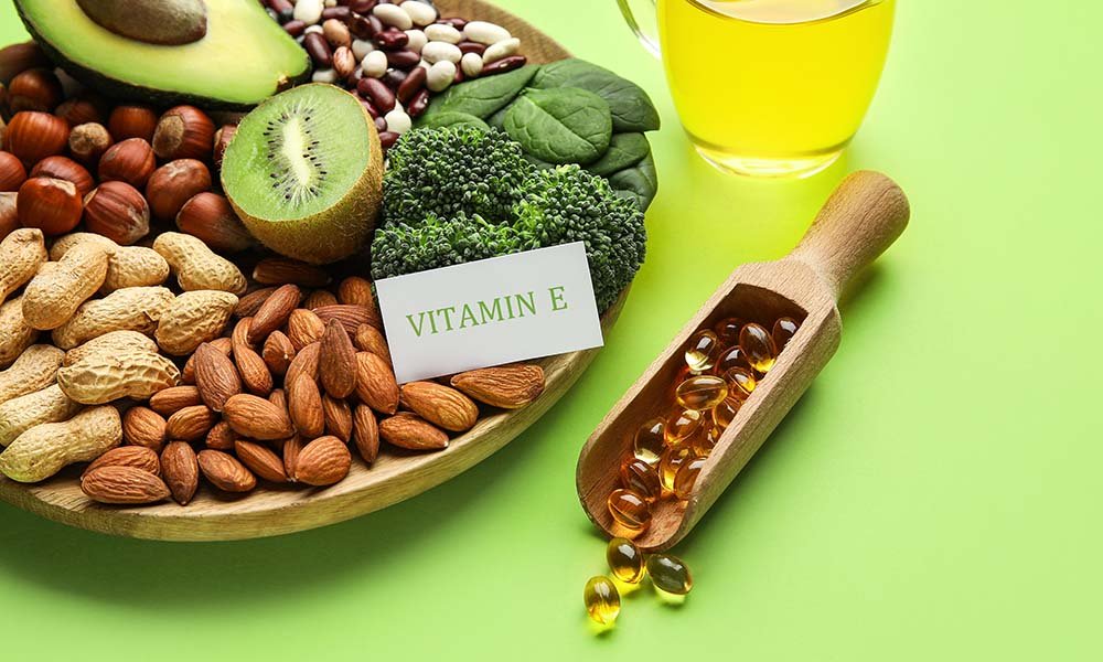 Vitamin E foods and softgels arranged on a green background