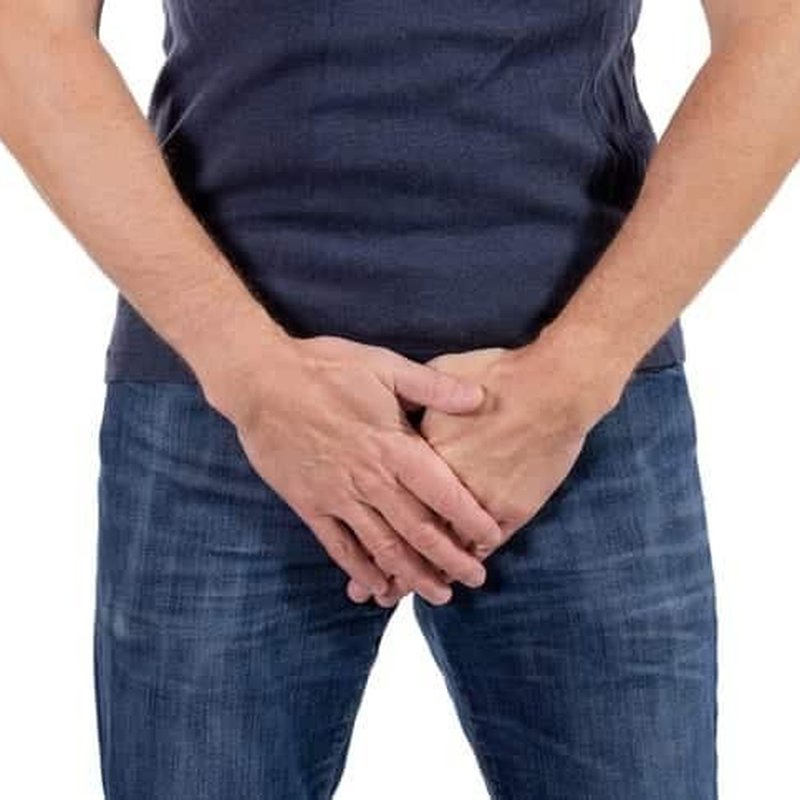 Man holding lower abdomen, representing urinary symptoms associated with BPH