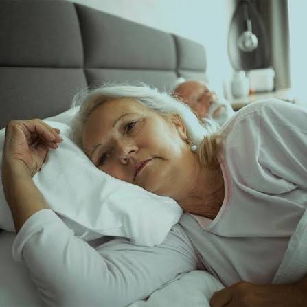 Woman lying awake in bed while partner sleeps