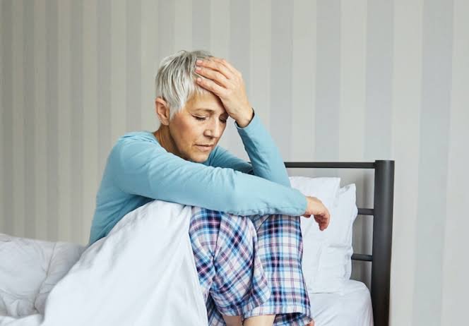 Woman sitting in bed looking tired after interrupted sleep